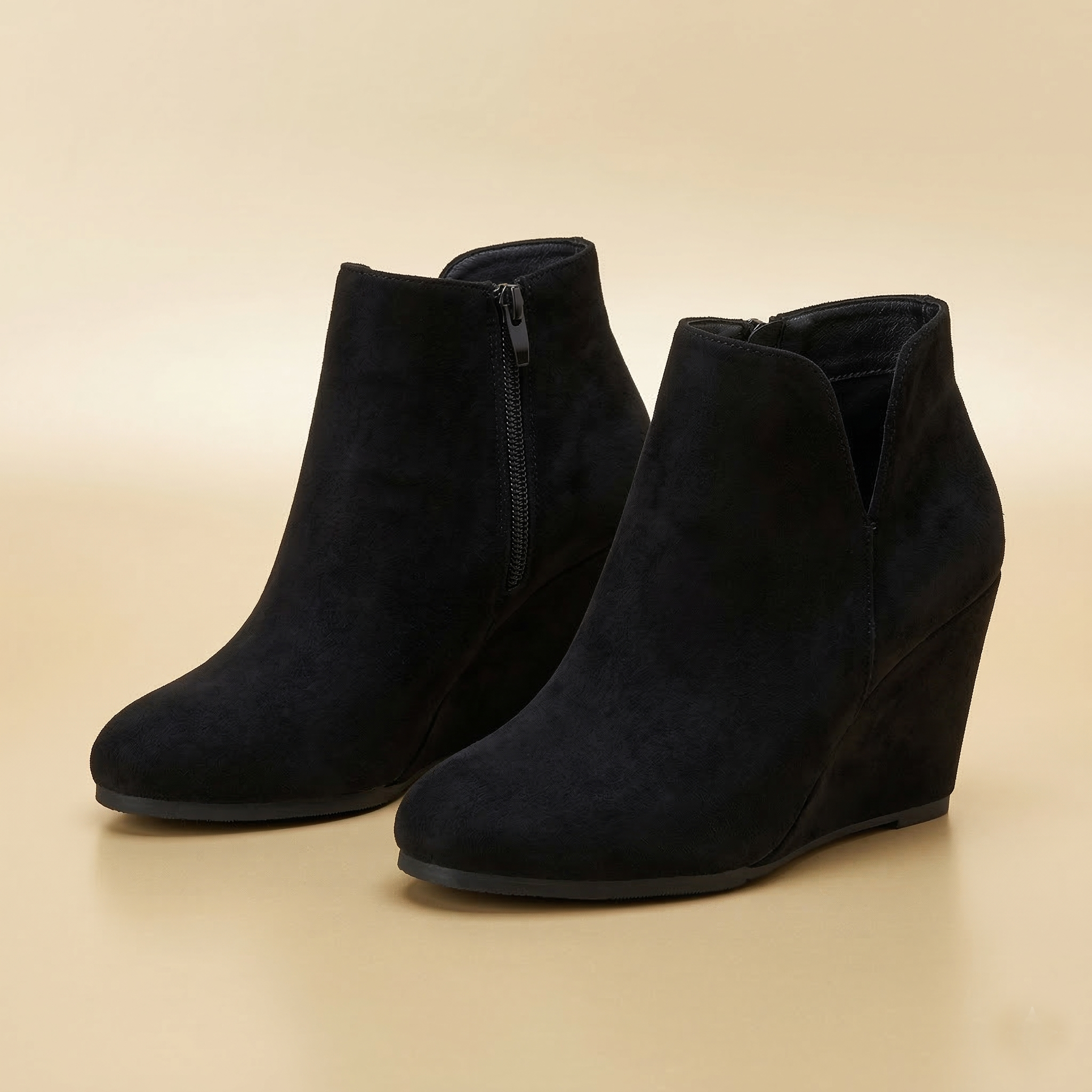 Black wedge ankle boots on a beige background